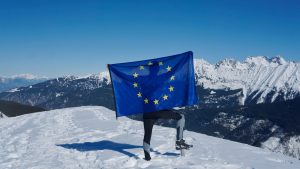 a man holding a flag on top of a snow covered mountain